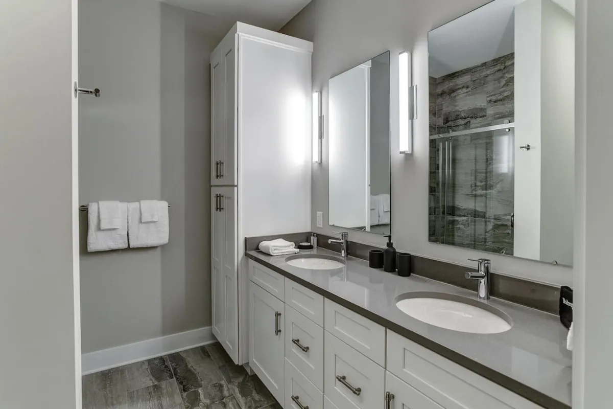 A modern ensuite bathroom featuring a double sink vanity with large mirrors and elegant lighting fixtures. The space exudes both functionality and luxury, making it ideal for morning routines or unwinding after a busy day.